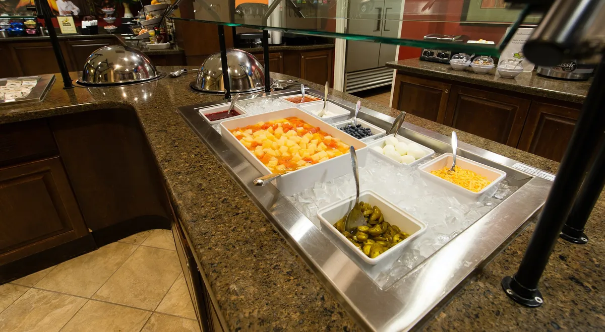 A vibrant self-serve salad bar featuring fresh fruits and a variety of toppings, inviting guests to enjoy communal dining. The cheerful setting encourages mingling and group interaction, perfect for fueling up before heading to a game or winding down after a city event.