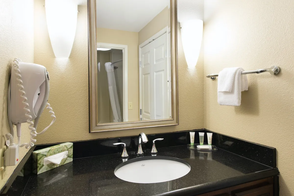 A sparkling bathroom is shown with a bright sink, wide mirror, and modern light fixtures. The space is clean and well-appointed, suggesting fresh towels, complimentary toiletries, and thoughtful amenities for personal care and relaxation.