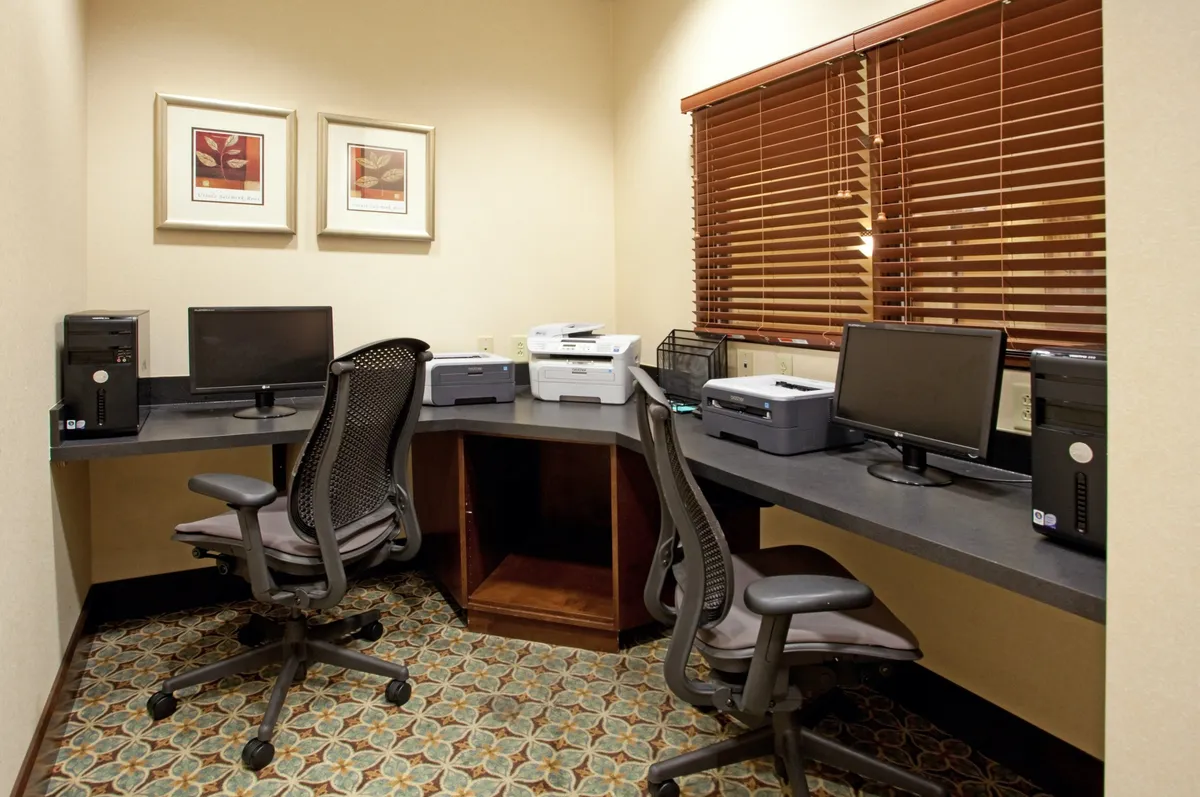 An organized business center featuring multiple computers, printers, desks, and modern decor. The space is clearly designed for productivity, supporting business travelers' needs for work, meetings, and collaboration.