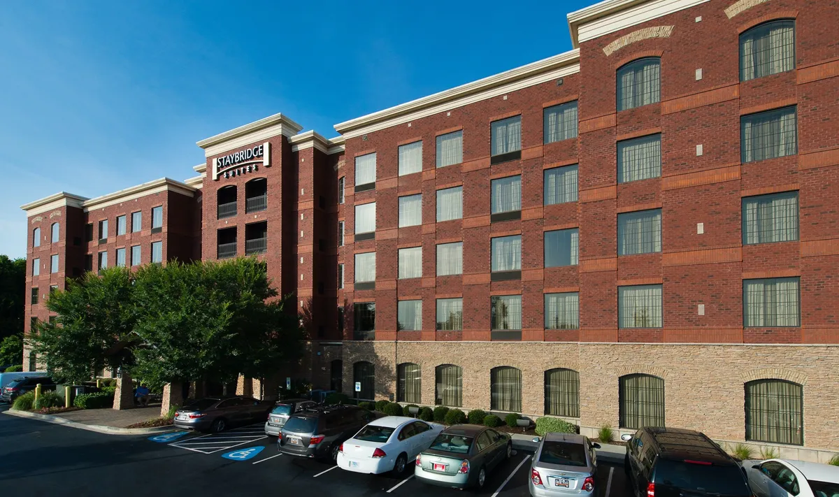This exterior shot showcases the hotel’s large windows, distinctive brick facade, and prominent entrance signage. The friendly ambiance hints at both business and leisure travel, and the surrounding area subtly suggests walkability to nearby restaurants, museums, and shops.