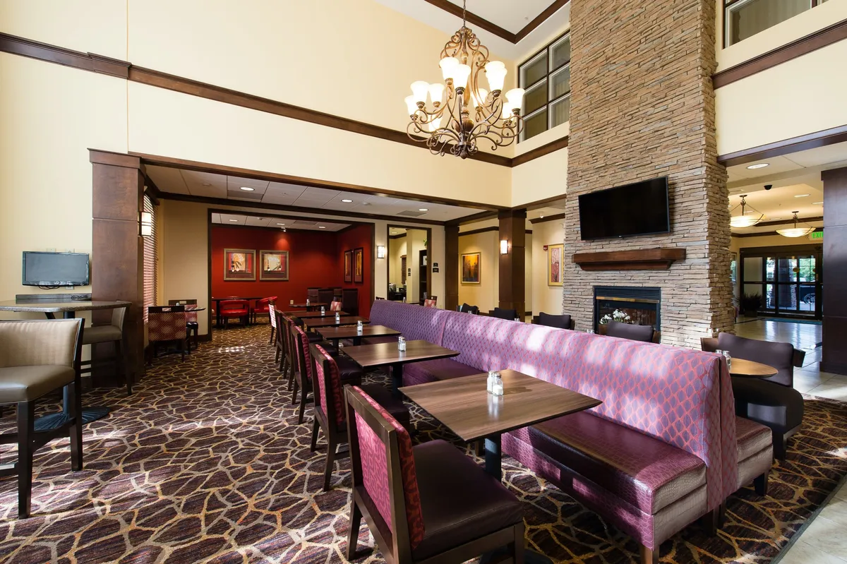 This image showcases a welcoming seating area centered around a fireplace, with a glowing chandelier above. Comfortable chairs and a cozy ambiance set the stage for small group gatherings, pre-game socializing, or relaxed post-event winddowns.